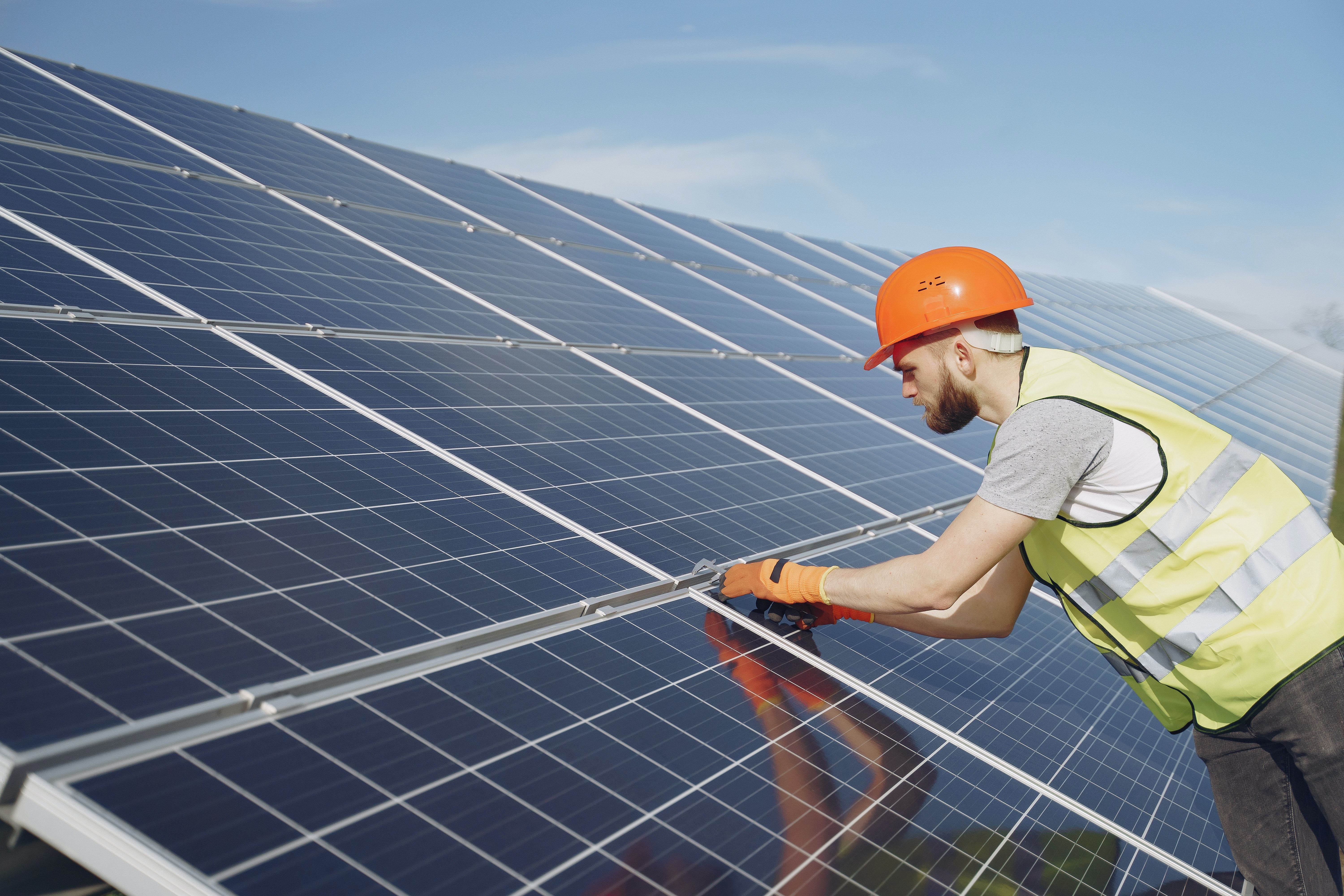 Engineer leaning over a solar panel helping to install it.  