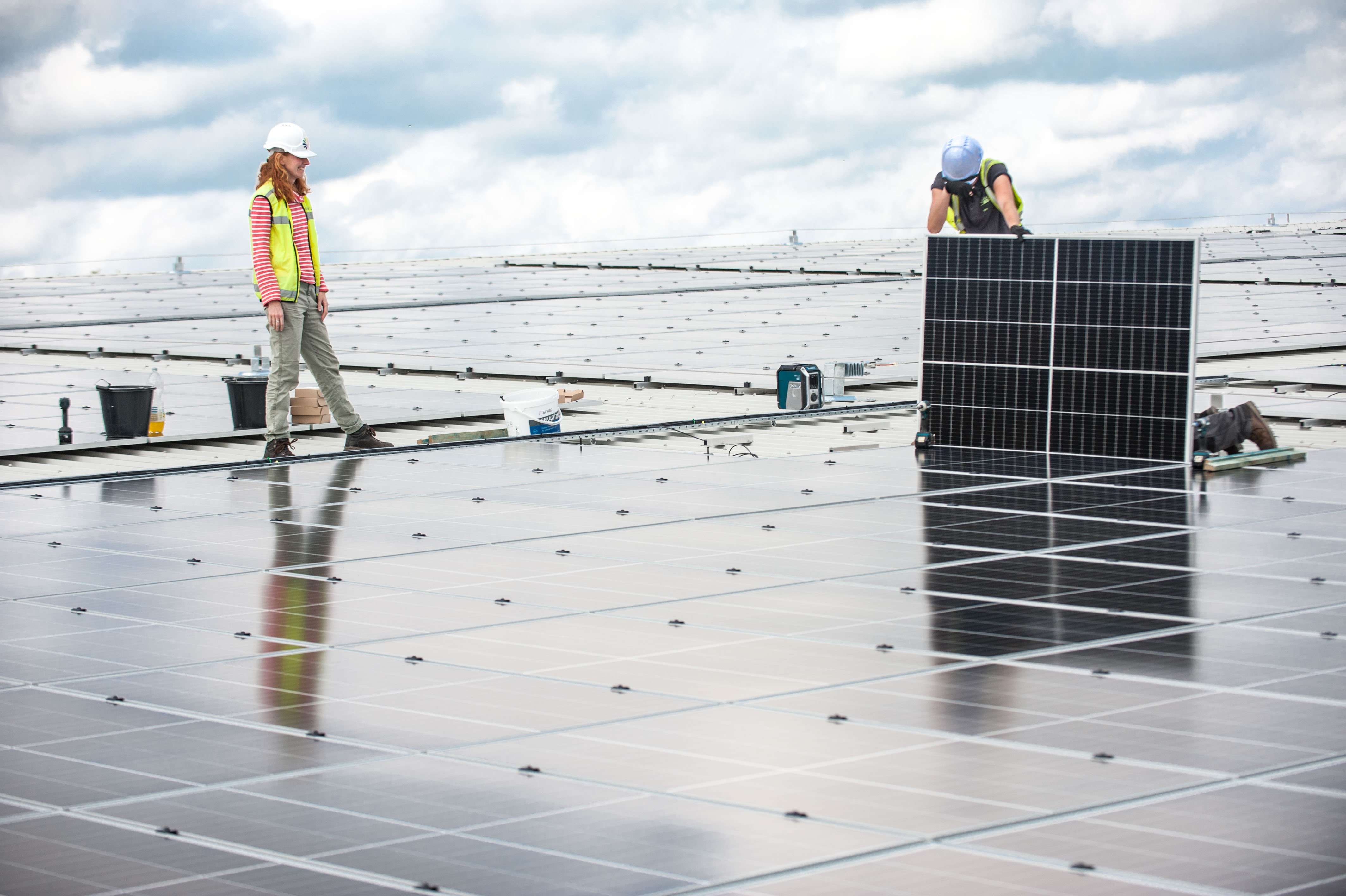 Engineers installing solar panels on a factory roof