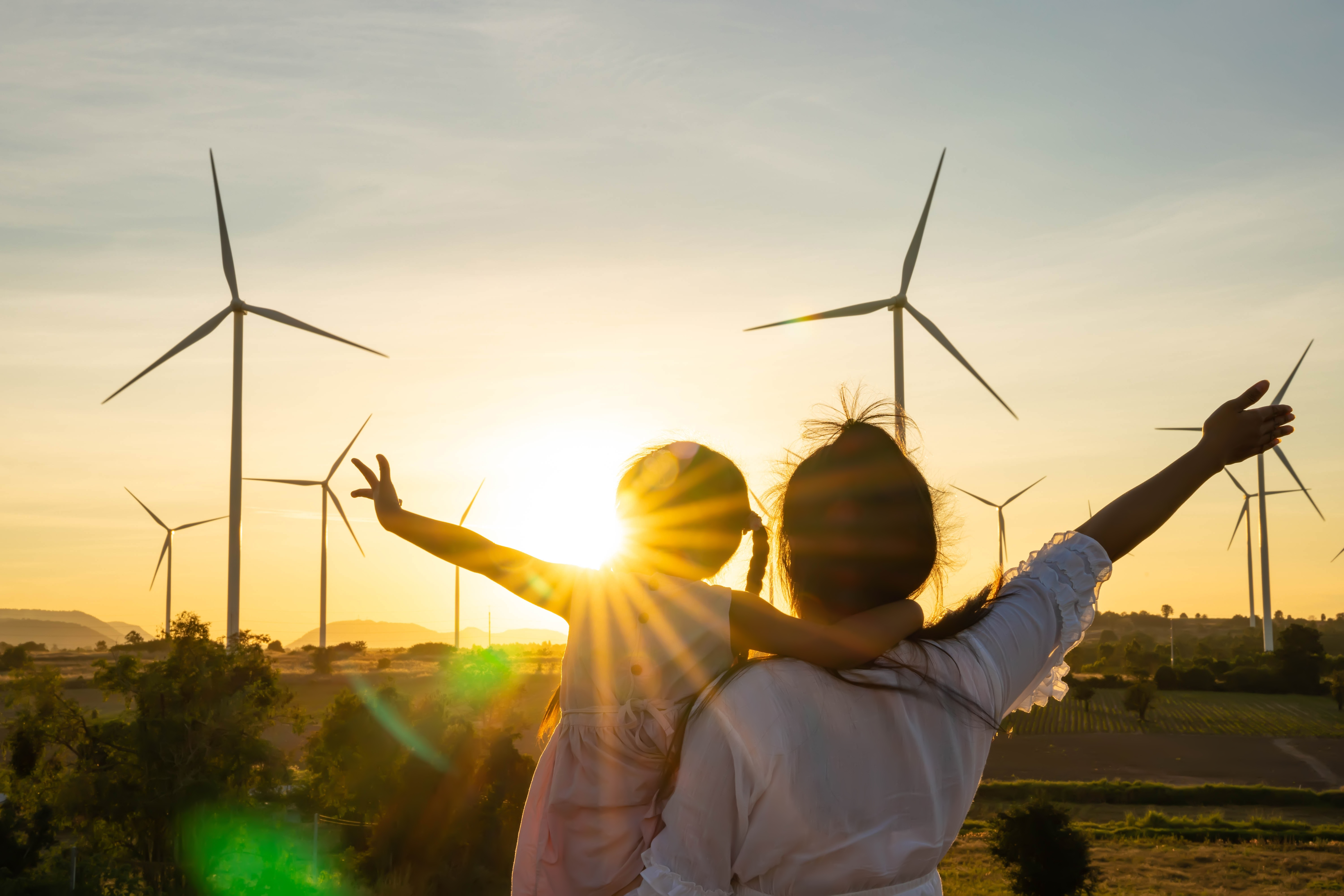 Mother and Child in front of wind turbines during sunset.