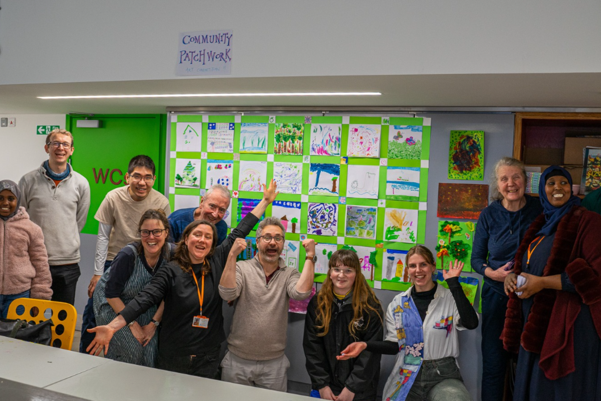 Teachers in a workshop in a green classroom with art on the walls.