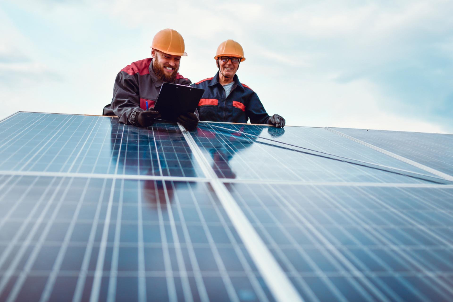 Two engineers with clipboards working on solar panels.