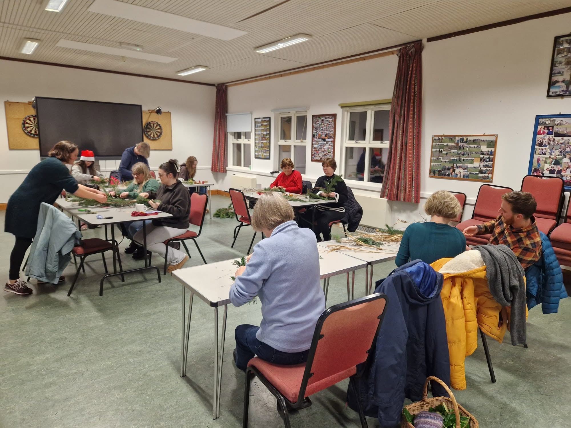 Tables of people participating in a community workshop in a bright village hall.