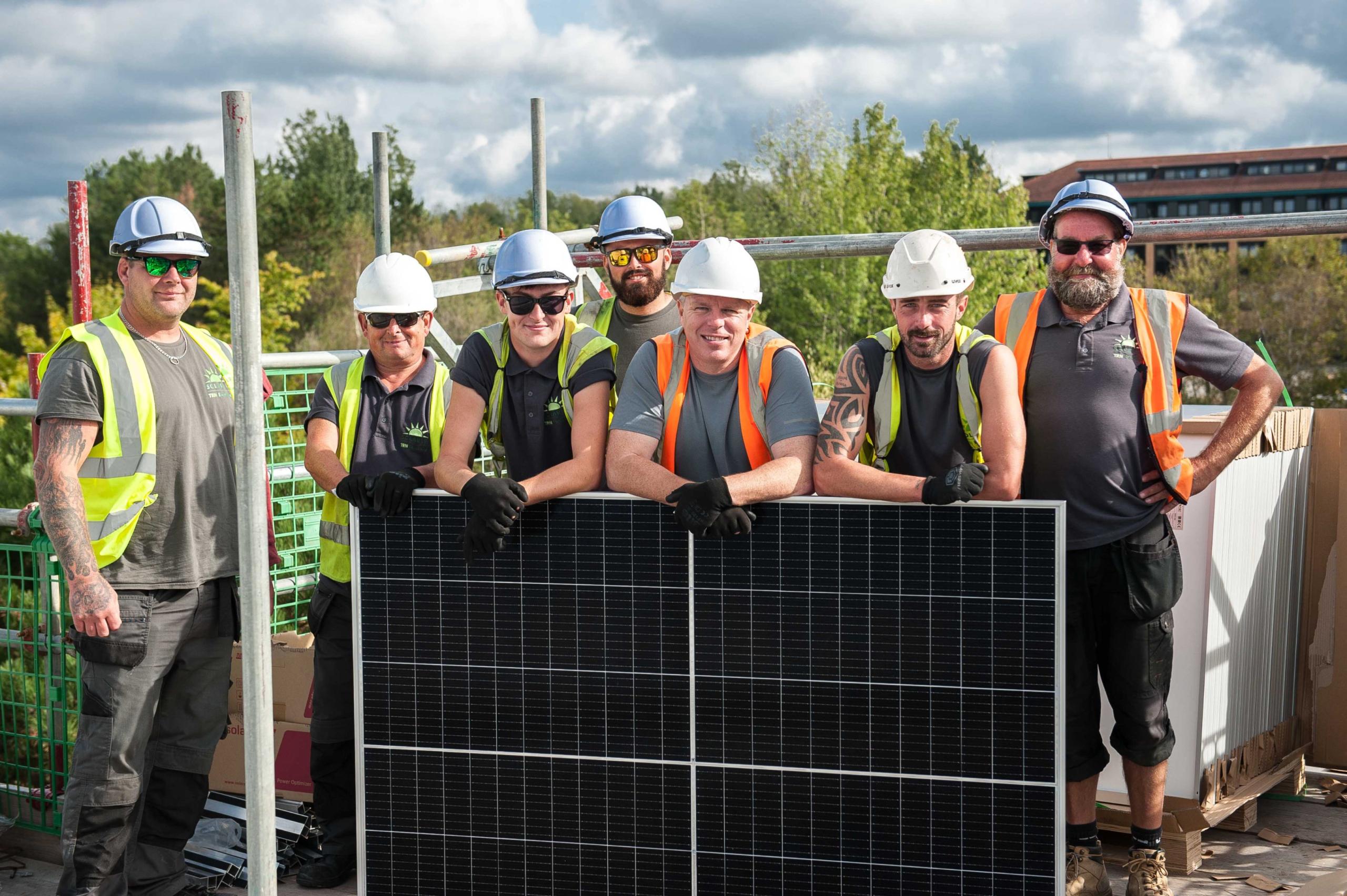 Engineers stood behind solar panels on the factory roof.