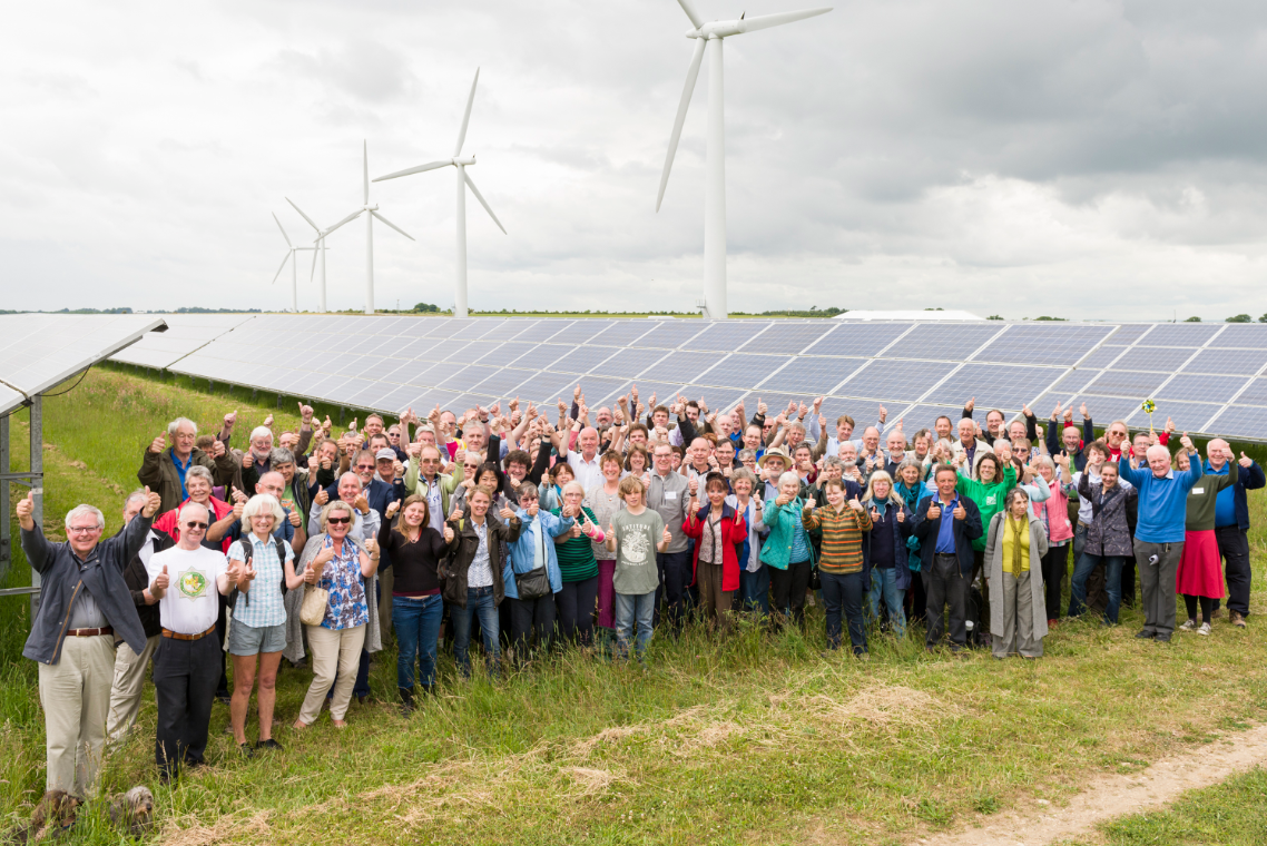 Westmill Energy members stood in a grassy field by their solar panels.