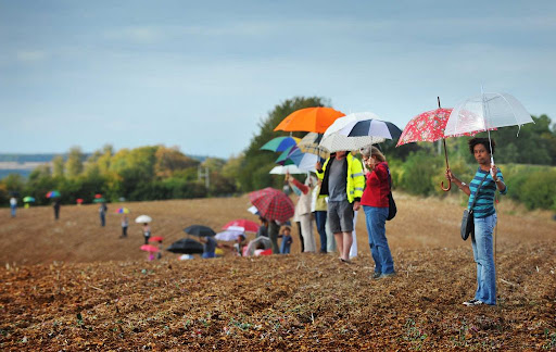 Community members standing in a field holding umbrellas to represent solar panel placement during Southill Solar’s ‘Bring Your Brolly Day’ campaign.
