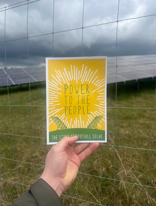 The Southill Solar booklet displayed in front of solar panels on-site, showcasing the project’s achievements and location.