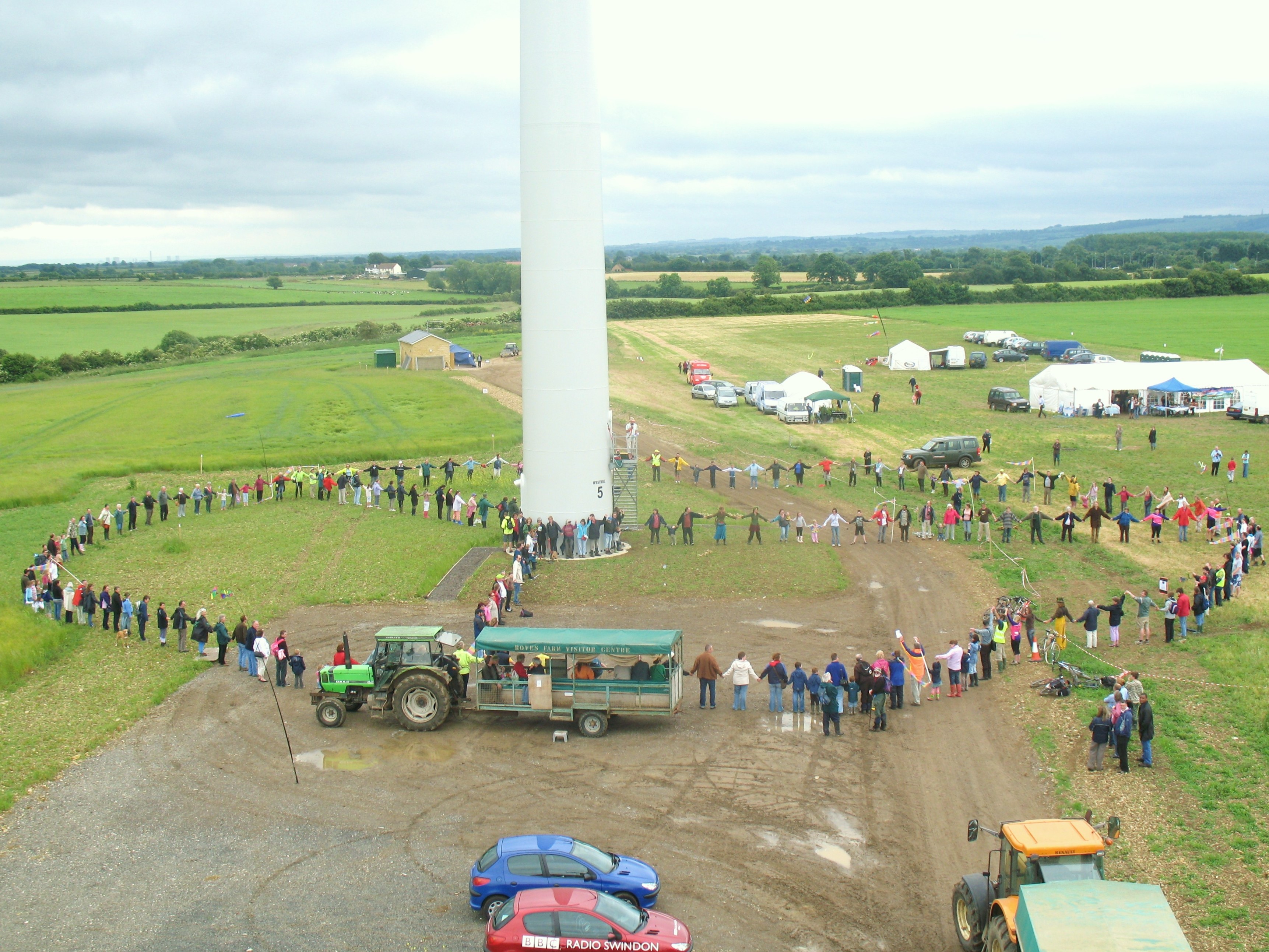 embers of the Westmill Wind Co-operative standing around their turbine, celebrating their community-driven renewable energy project.