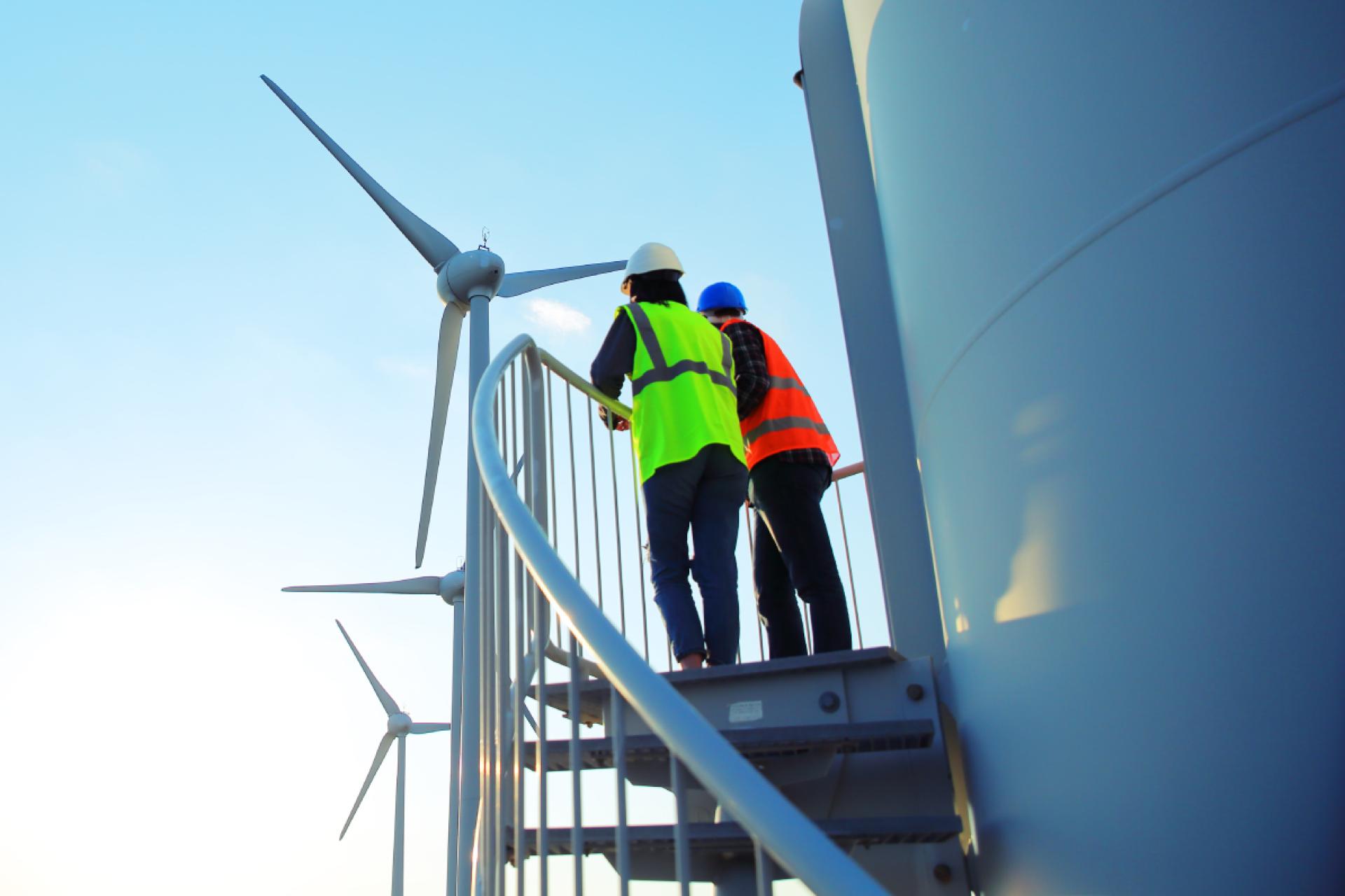 Wind turbine with engineers climbing the stairs for maintenance or inspection.