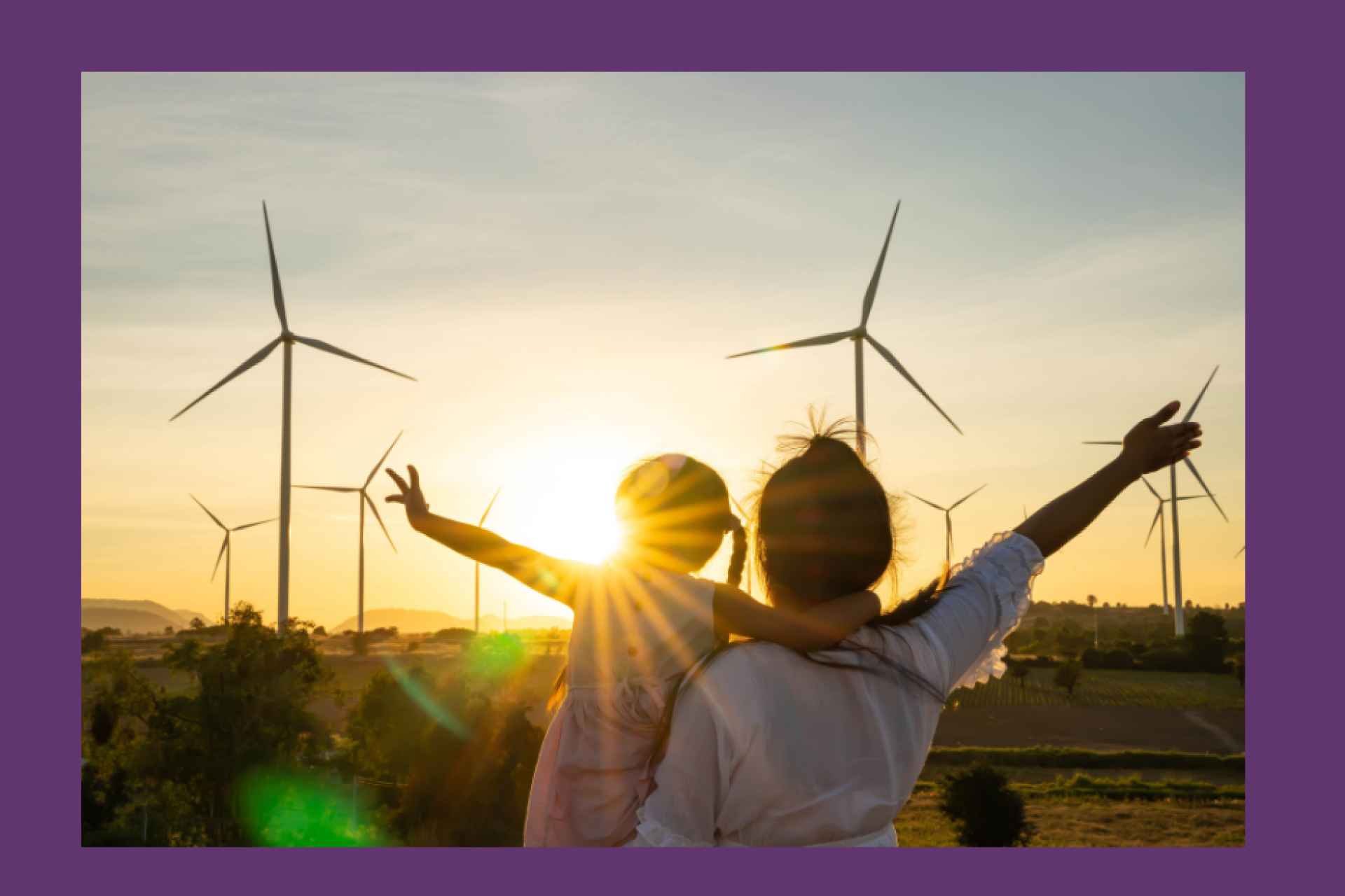 Family stood infront of a wind farm at sunset