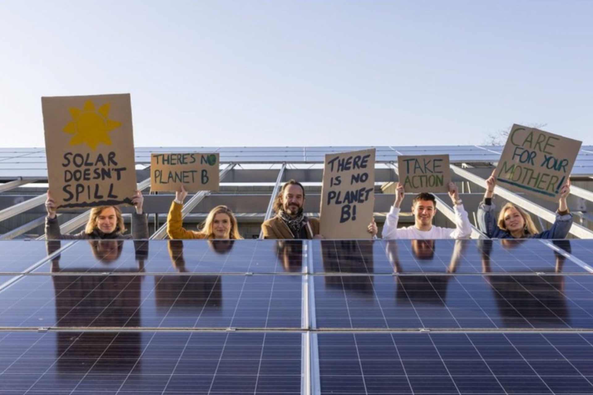 Younity holding signs of support infront of solar panels 