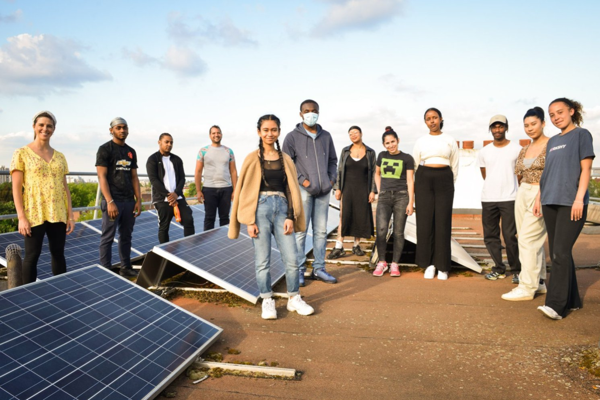 Energy garden group standing proudly in front of rooftop solar panels at their site