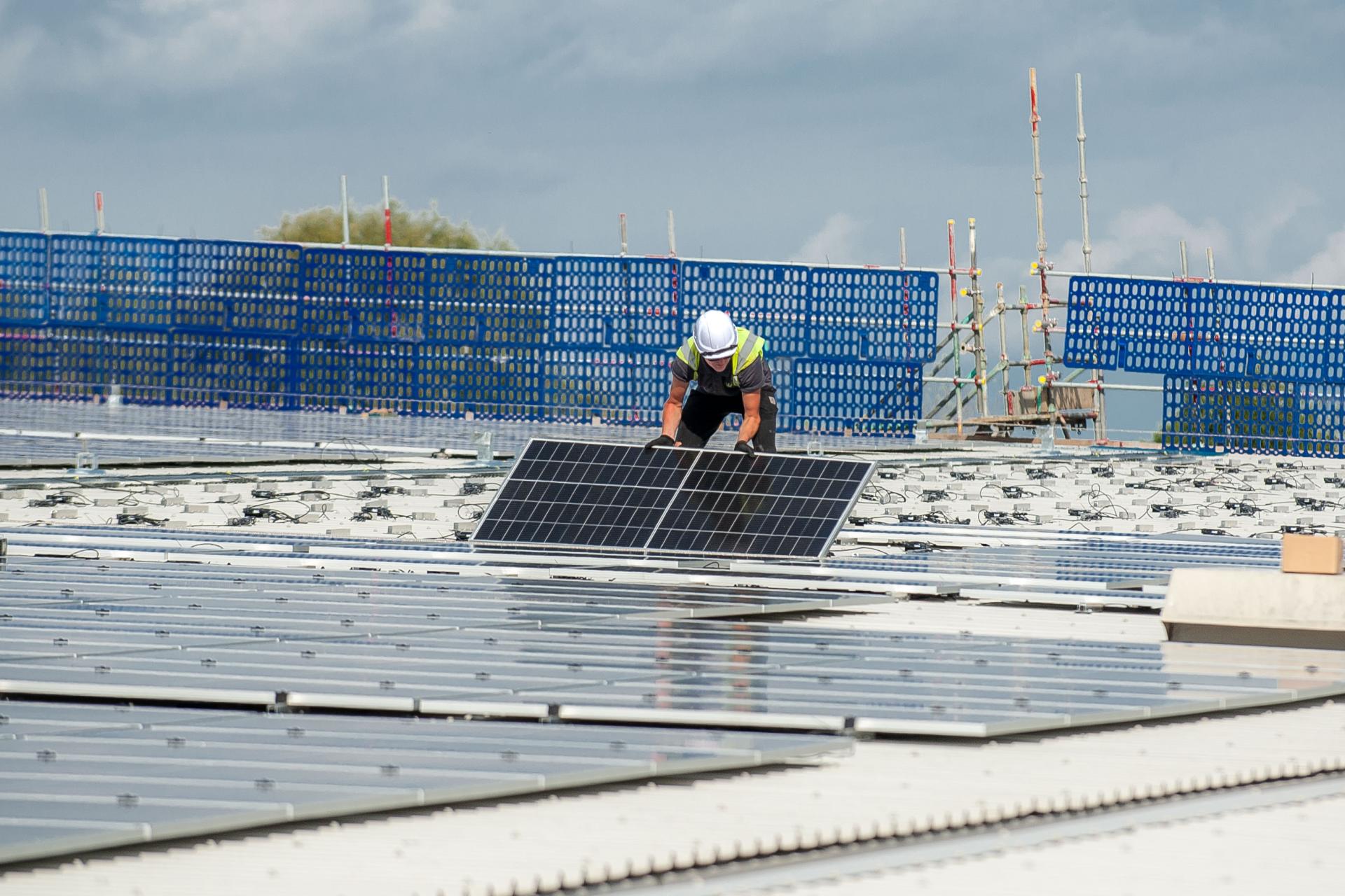 Engineers installing solar panels on the roof of the studio building.