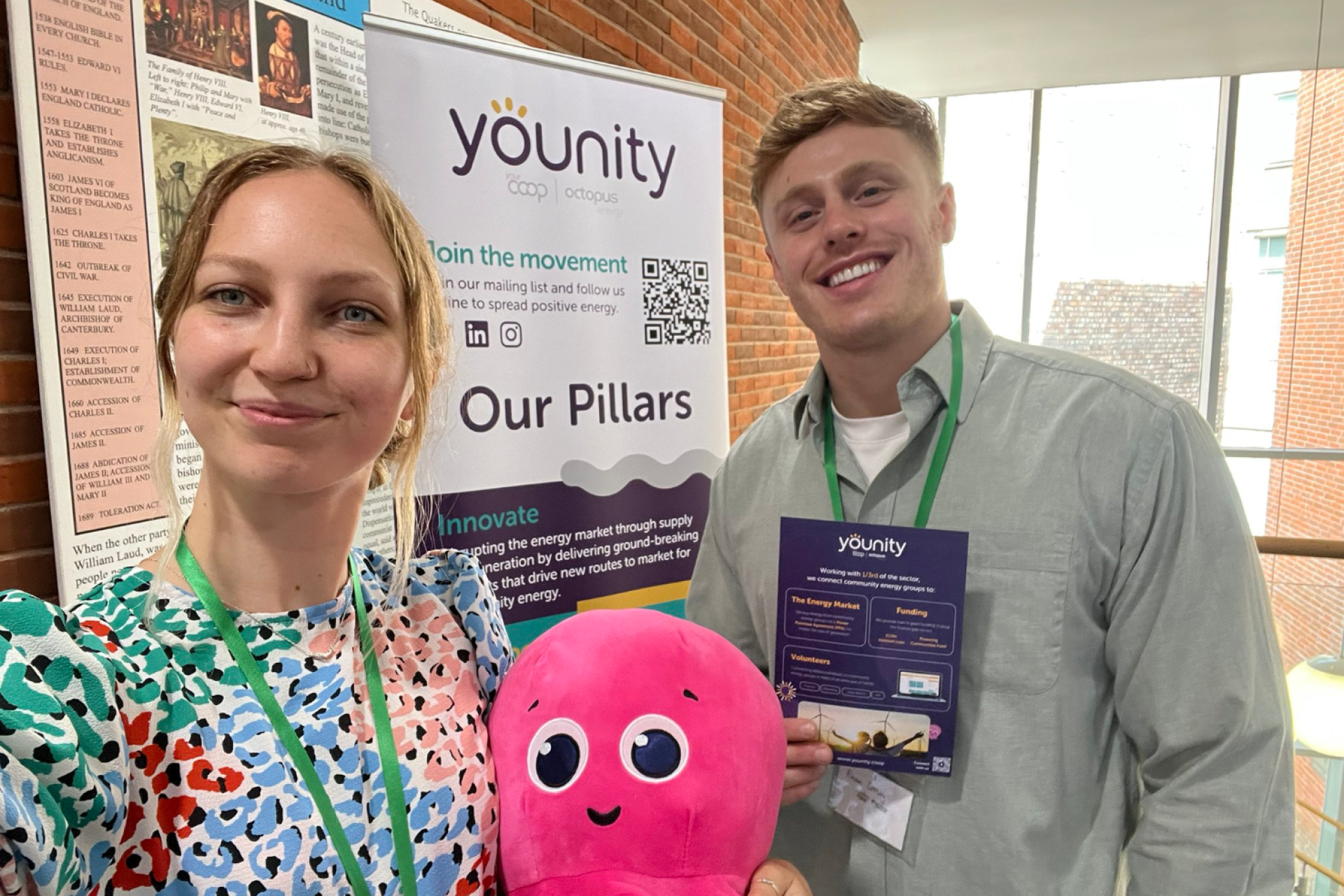 Younity colleagues posing in front of a banner at an event