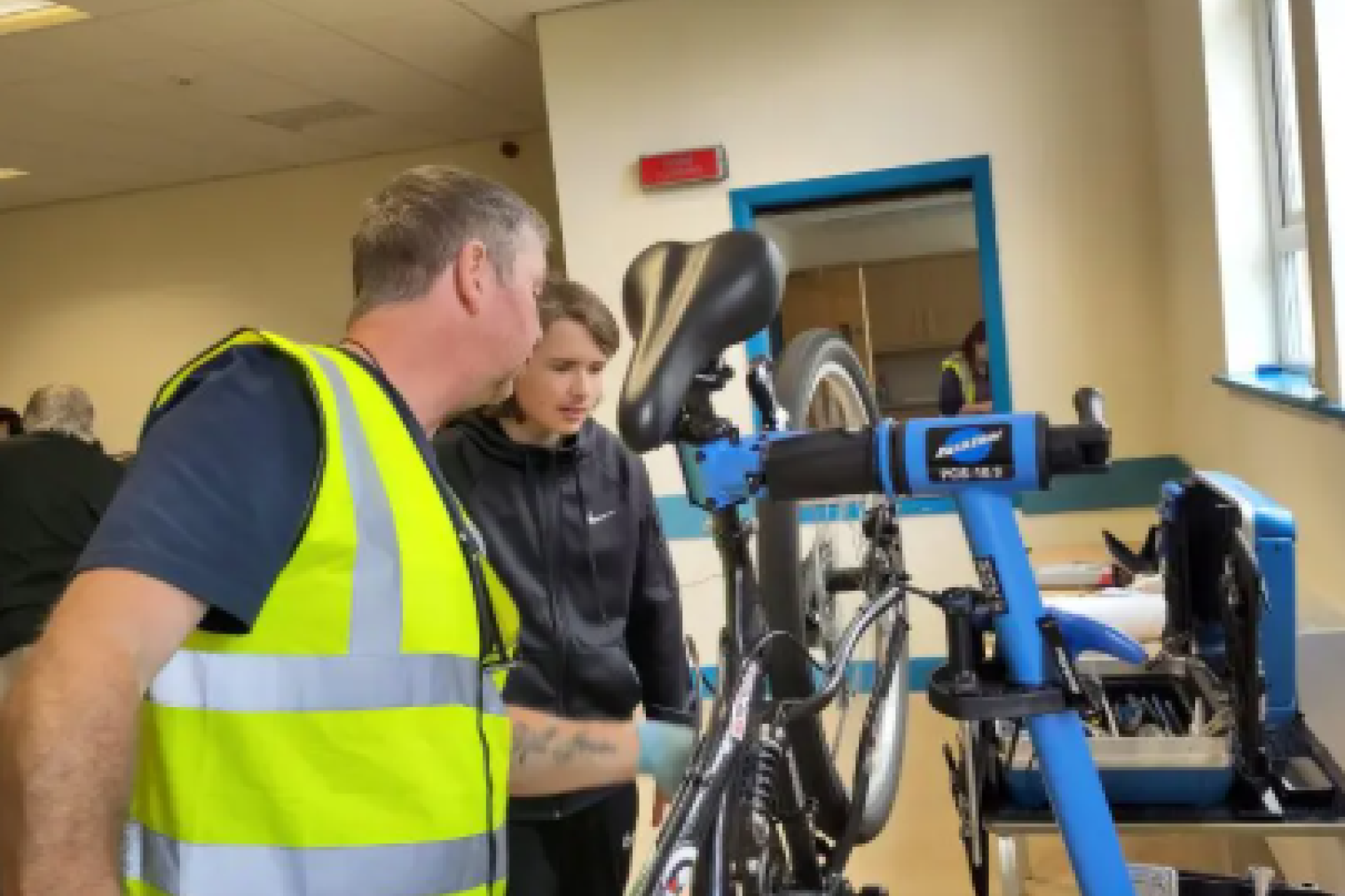 A volunteer teaching a boy how to repair a bike.