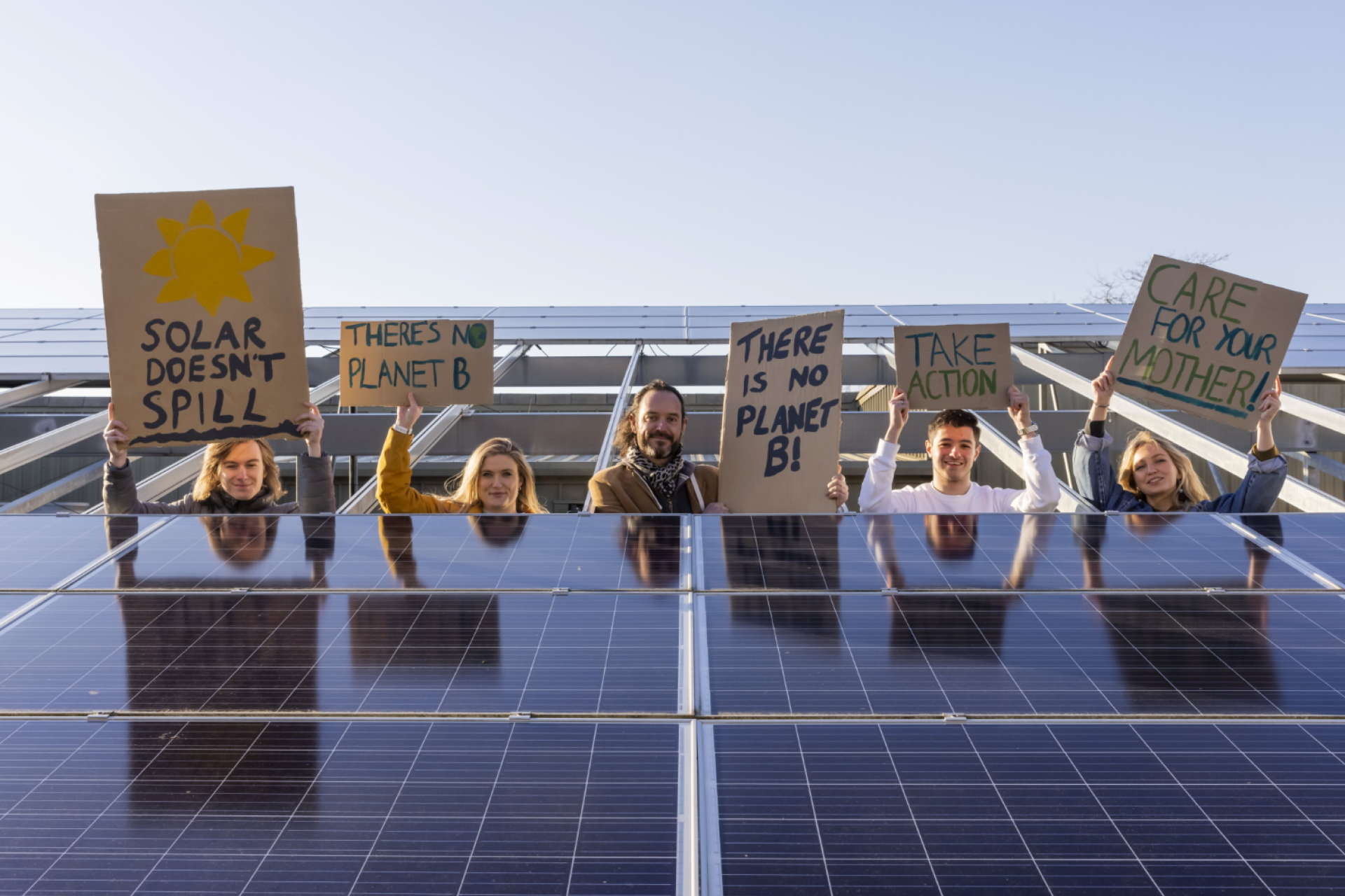 Community energy volunteers holding signs next to solar panels.