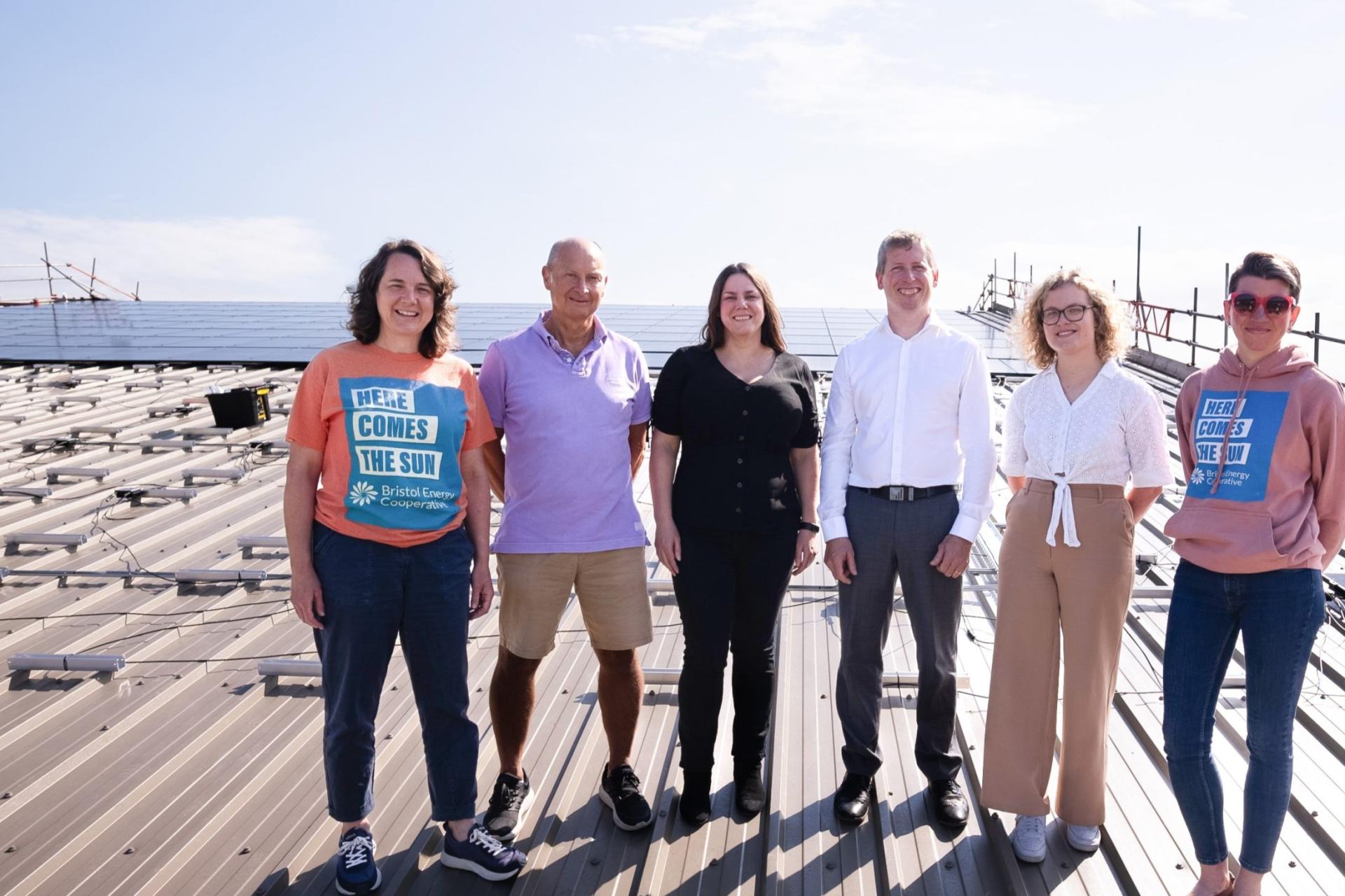 Bristol Energy Co-op team members standing on a roof beside one of their solar assets.