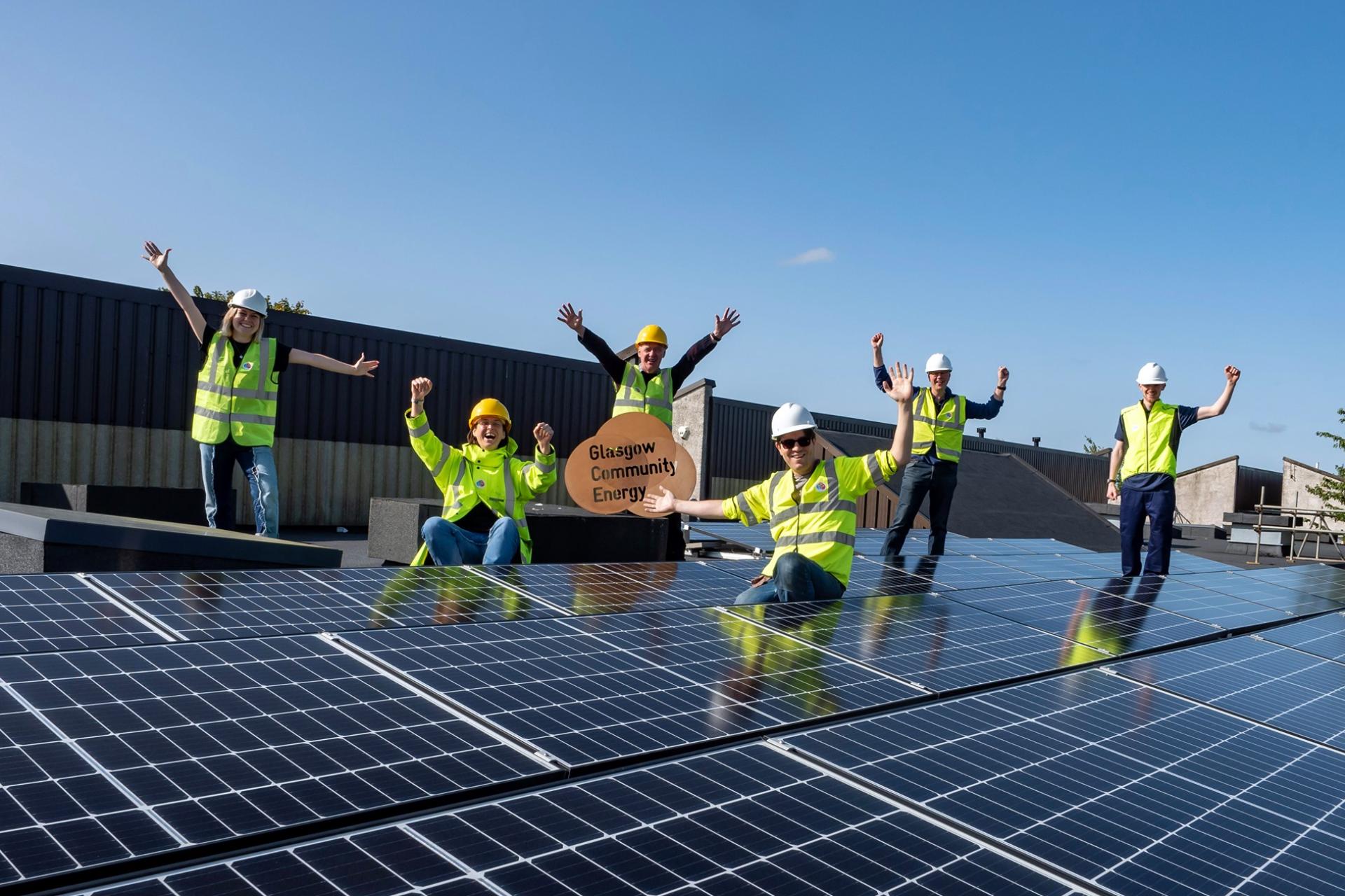 Glasgow Community Energy group seated in front of their solar panels.
