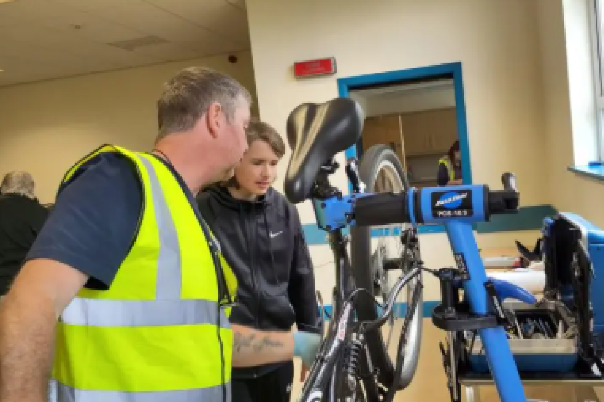 A mechanic shows a young boy how to fix a bike.