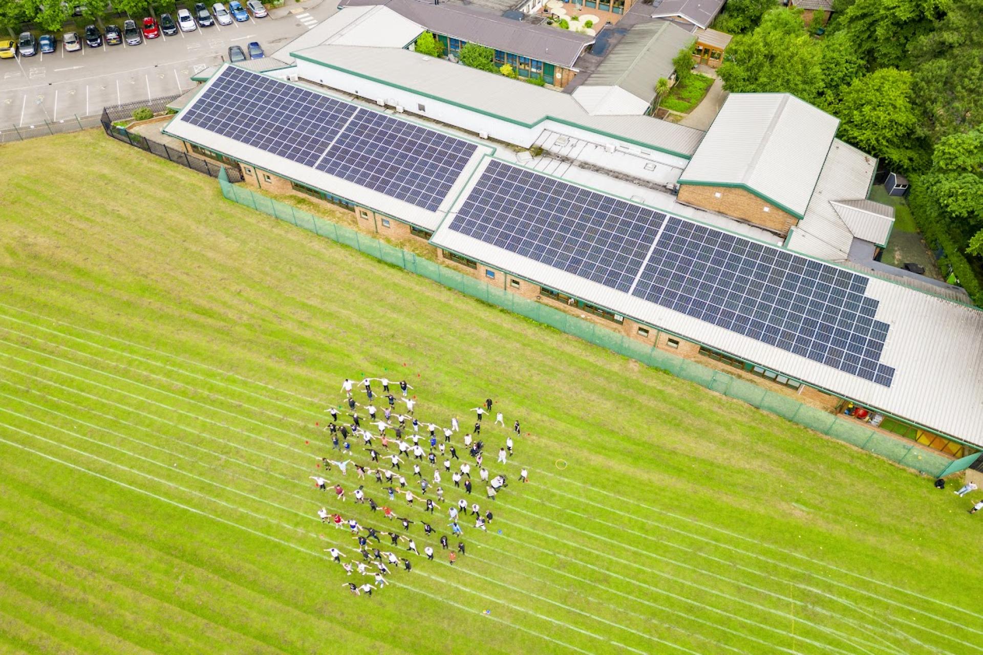 School children posing proudly with solar panels on their school.
