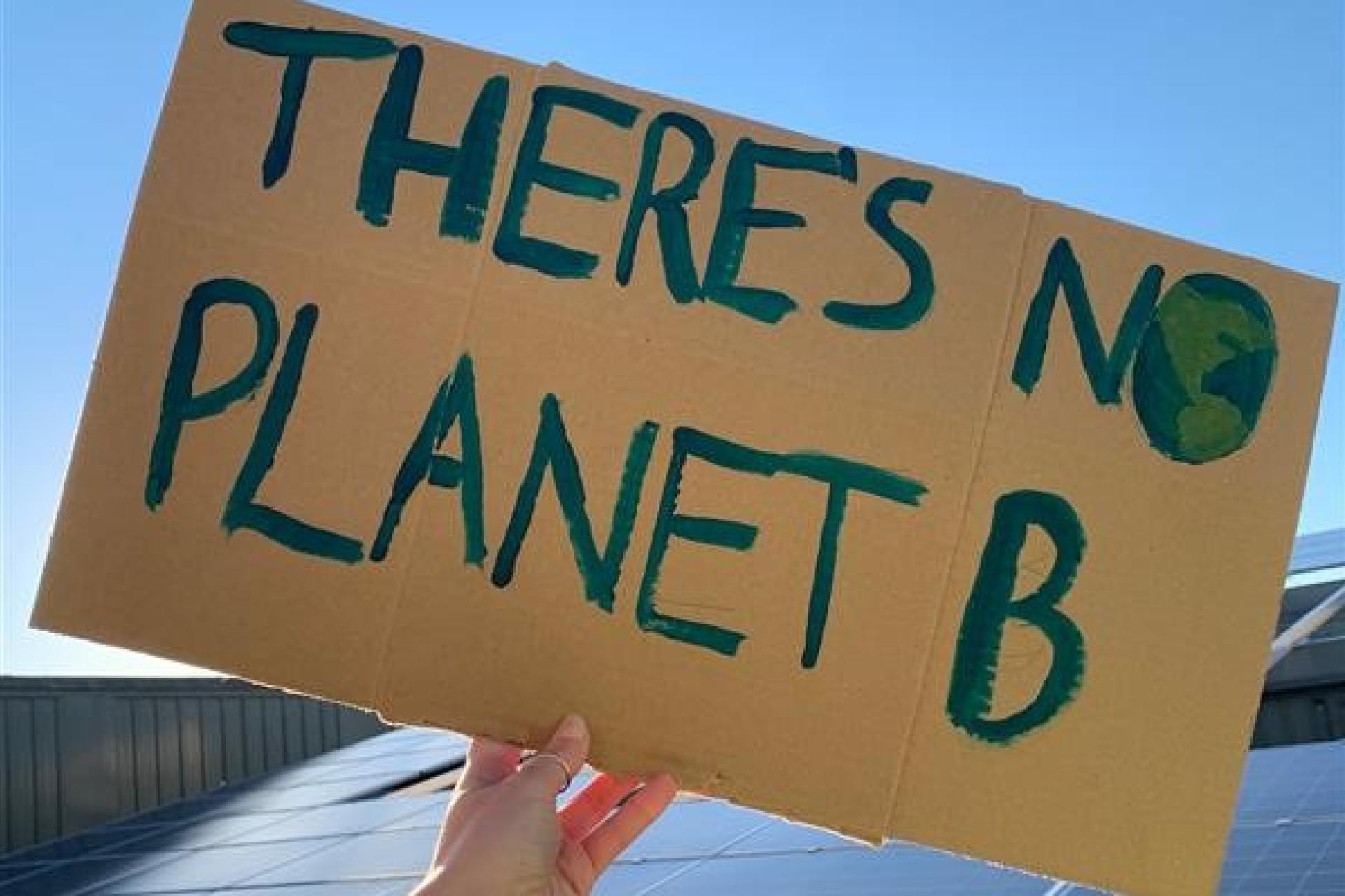 Person holding a sign that reads “There is no Planet B.”