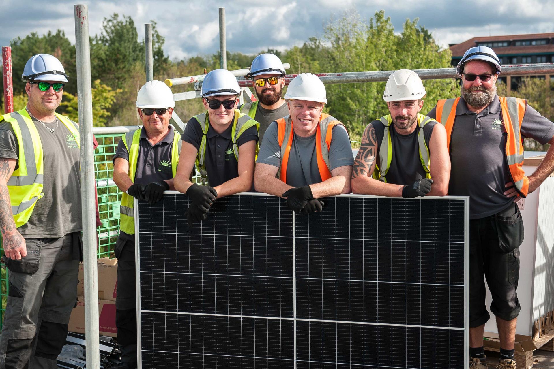 Group of engineers posing during a rooftop solar installation.