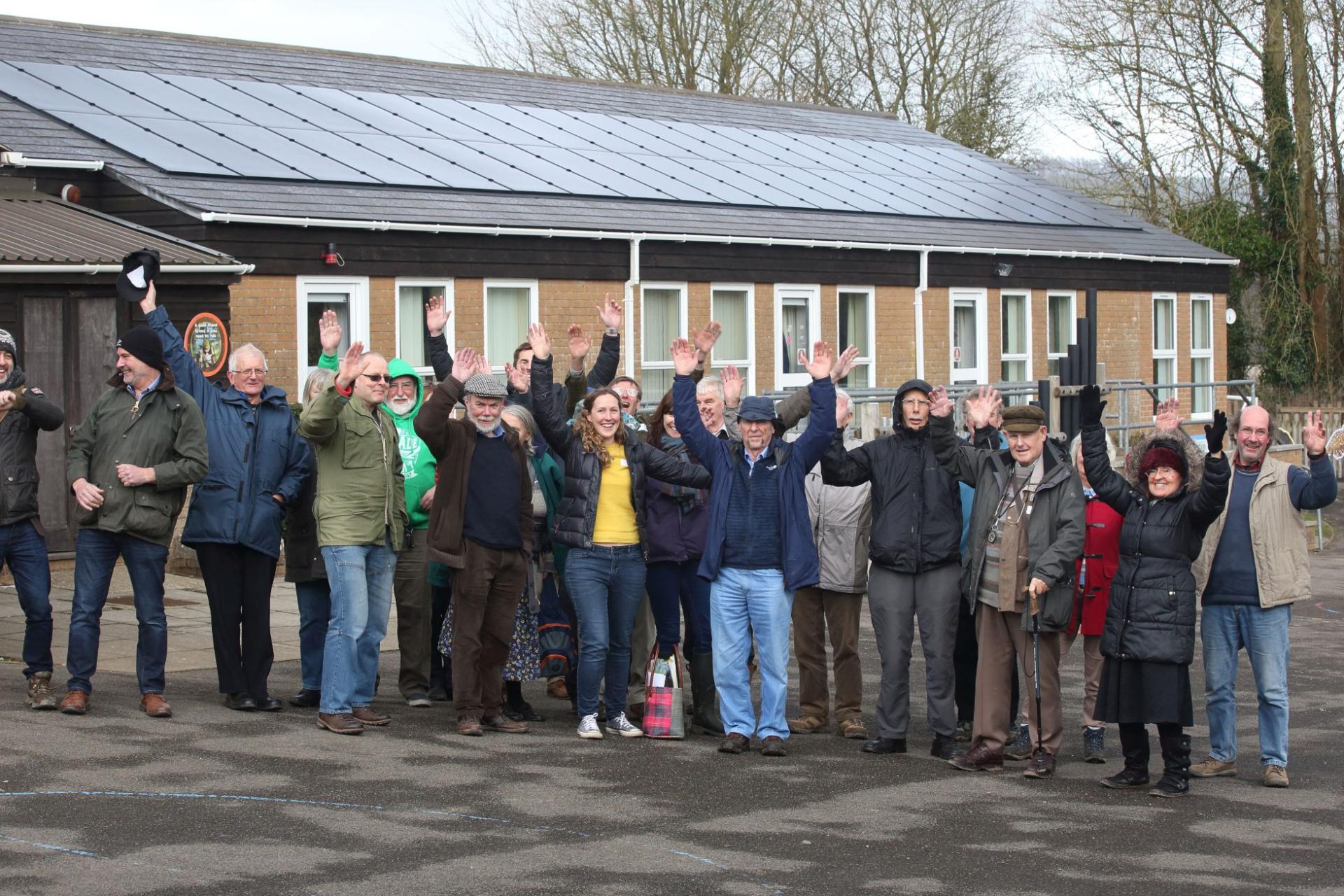 Dorset Community Energy Team stood infront of a school they helped put solar panels on.