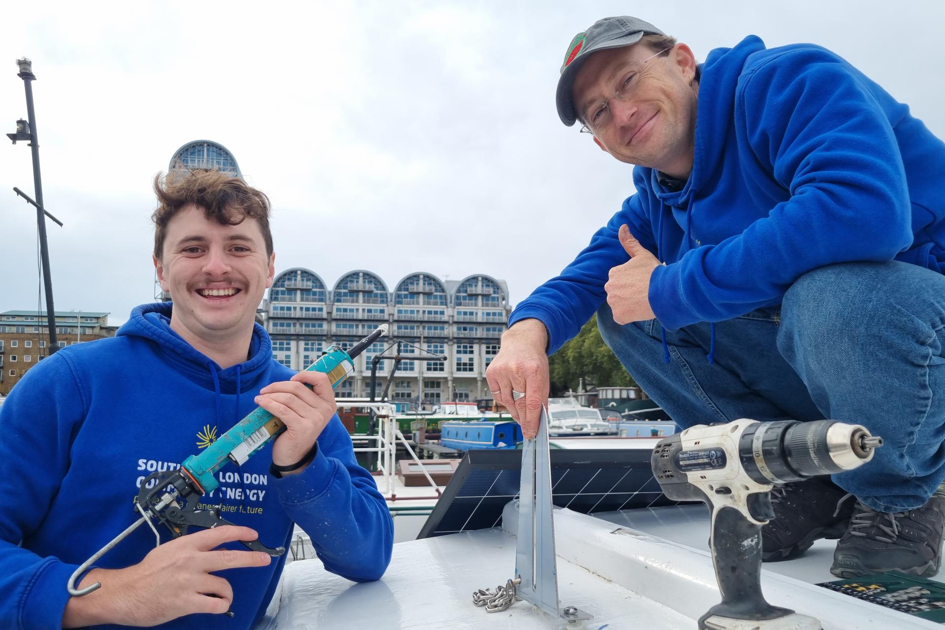 Two SELCE team members with tools installing solar panels.