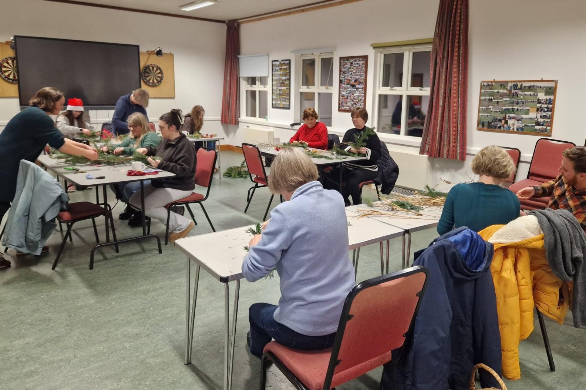 A small group of residents sit around a table, smiling and chatting during an interactive workshop.