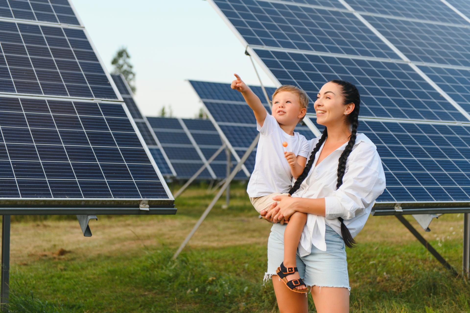 A mother and daughter stood in front of solar panels in a field. 