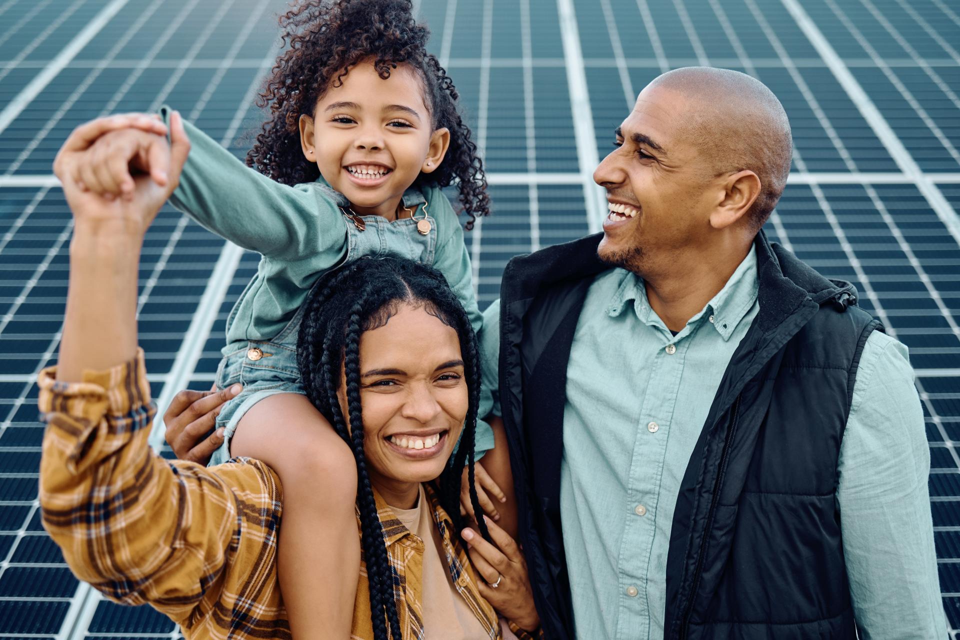 A young family stood in front of solar panels smiling.