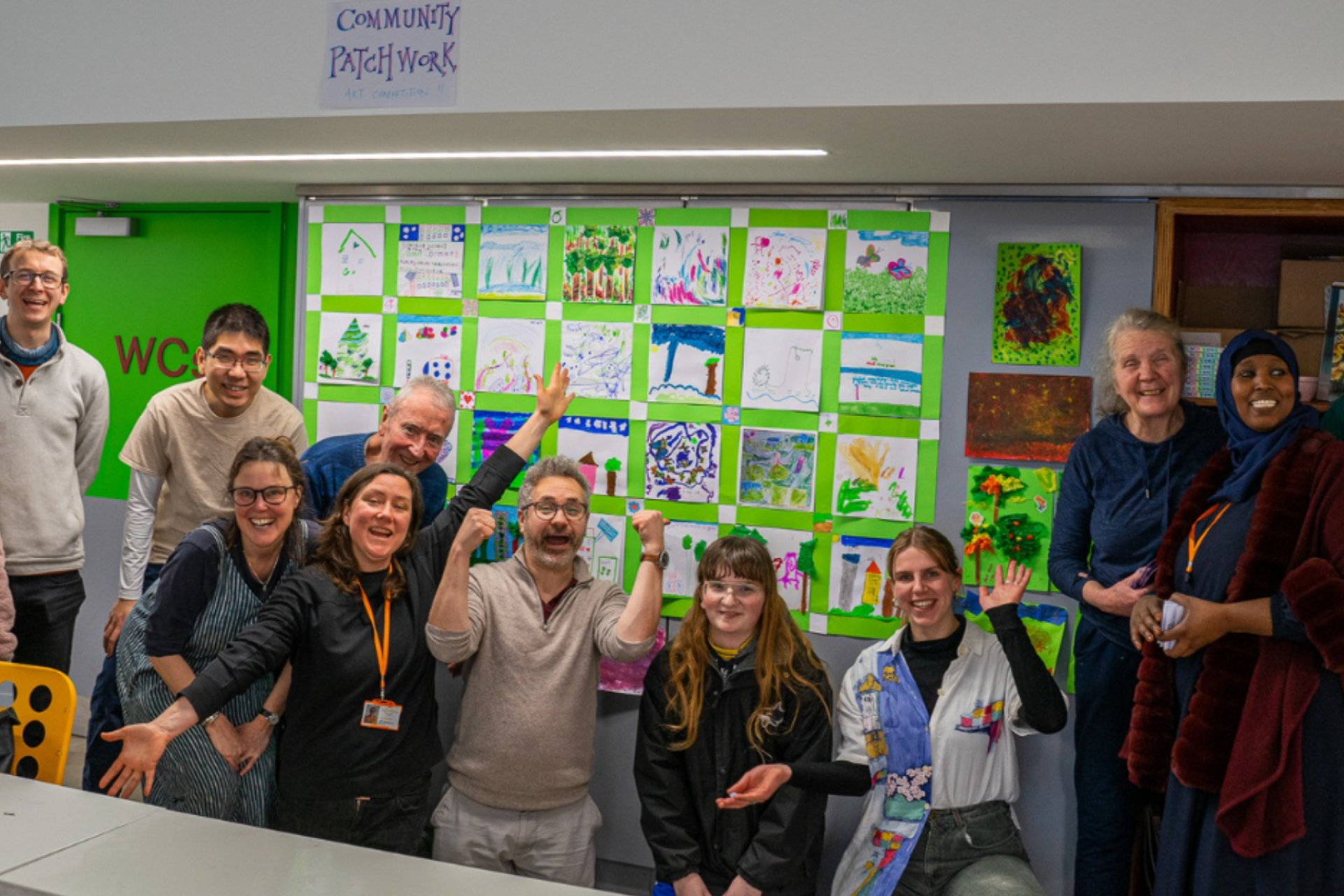 Teachers in a workshop in a green classroom with art on the walls.